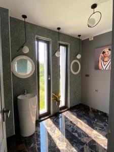 NORD APARTAMENTS في زالاو: حمام مع حوض ومغسلة ونوافذ