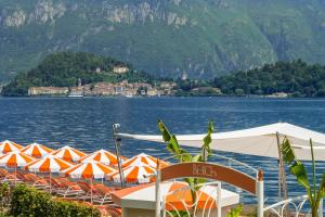 a bunch of orange and white umbrellas next to a lake at Grand Hotel Tremezzo in Tremezzo