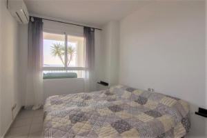 a bedroom with a bed and a window with a palm tree at Villamarina dúplex en primera línea de mar - Fincas Arena in Benidorm +16 photos