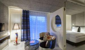 a bedroom with a bed and a window and chairs at Mini-suites Le Rêve in Kirrwiller