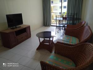 a living room with chairs and a tv and a table at Pangkor fun fun fun apartment in Pangkor
