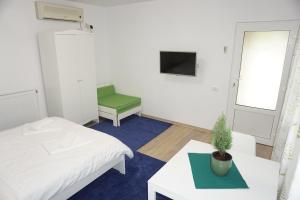 a room with two beds and a table and a tv at Casuta Bradulet - Aeroport Otopeni & Therme in Baloteşti