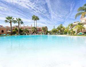 una grande piscina con palme sullo sfondo di Apartamento entre Marbella y Estepona a Estepona