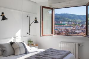 a bedroom with a bed and a large window at Bilbao Sensations.OLD TOWN exclusive views&parking in Bilbao +16 photos