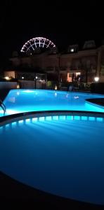 a swimming pool at night with a ferris wheel in the background at B&C Apartments LA POSTA Home in Lido di Jesolo