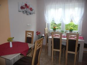 ein Esszimmer mit einem Tisch, Stühlen und einem Fenster in der Unterkunft Pension Andrea in Lugau