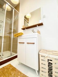 ein weißes Bad mit einem Waschbecken und einer Dusche in der Unterkunft Le Wood, entre centre ville et plage in Mers-les-Bains
