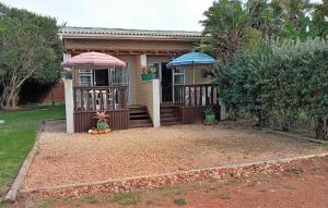 a house with two umbrellas on the front of it at Anchorage Cottage & The Moorings in Cape St Francis