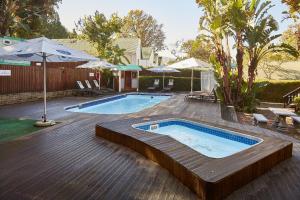 a swimming pool with a wooden deck with an umbrella at First Group Knysna River Club in Knysna