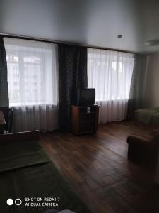 a living room with a flat screen tv and curtains at Yedinstvo Hotel in Cherepovets