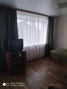 a room with a tv and a bed and a window at Yedinstvo Hotel in Cherepovets