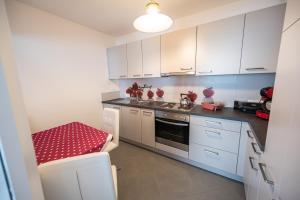 a small kitchen with white cabinets and a red stool at Sonnenplatzl-adults only in Fulpmes