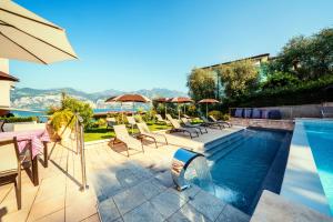 a swimming pool with chairs and umbrellas on a house at Hotel Antonella in Malcesine