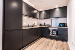 a kitchen with black cabinets and a wooden floor at Host & Stay - Chavasse Chambers in Liverpool