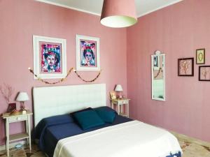 una camera con letto bianco e pareti rosa di Trinaco B&B a Catania