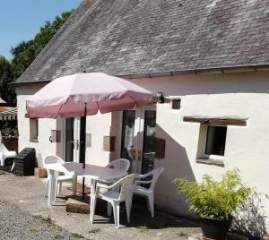 une table, des chaises et un parasol en face d'une maison dans l'établissement La Petite Maison, à Beauchêne