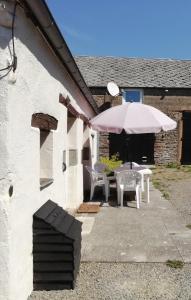 un patio con mesa y sombrilla en La Petite Maison, en Beauchêne