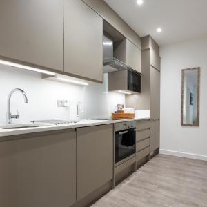 a kitchen with white cabinets and stainless steel appliances at Luxustay Milburn House in Milton Keynes