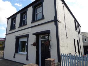 a white house with a black door and windows at Gwynedd House Flat 2 in Pentraeth