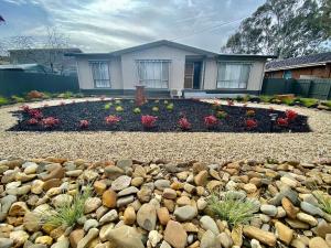 a house with a flower garden in front of it at Sevens Avenue Guest House in Euroa