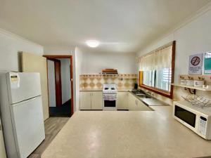 a kitchen with a white refrigerator and a microwave at Sevens Avenue Guest House in Euroa