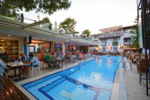 a swimming pool with people sitting at tables and a restaurant at Istankoy Hotel in Bodrum City