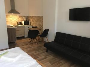 a living room with a black couch and a kitchen at Bogoly Apartman in Tokaj