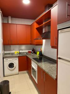 a kitchen with red cabinets and a washing machine at Ritual Sevilla Suites Alameda 1 in Seville