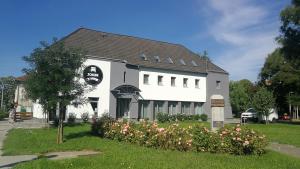 een wit gebouw met een zwart dak en wat bloemen bij Joker Panzió in Pécs