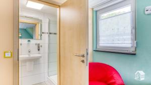 a bathroom with a red stool next to a sink at Pension zum Rothaarsteig in Netphen