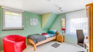 1 dormitorio pequeño con 1 cama y 1 silla roja en Pension zum Rothaarsteig en Netphen
