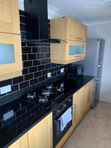 a kitchen with a stove and a black tiled wall at Sea view apartment in Cleethorpes