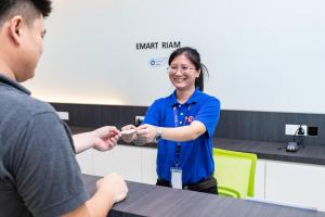 Een vrouw geeft iets aan een man aan een tafel. bij Emart Hotel (Riam) in Miri