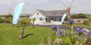una casa con signos azules en un patio con flores púrpuras en Bude Holiday Resort, en Bude