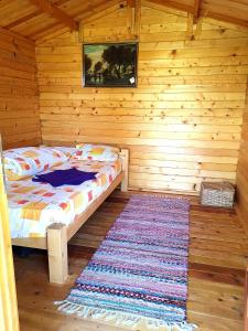 a bedroom with a bed in a wooden cabin with a rug at Retezat Retreat - wood cabin in Clopotiva