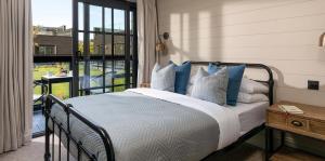 a bedroom with a bed with blue pillows and a balcony at Retallack Resort by Away Resorts in Padstow +62 photos