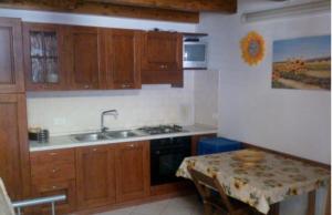 a kitchen with wooden cabinets and a sink and a table at Stanze Appartamento ROSINA casa vacanze Cannole sulla via Francigena in Cannole