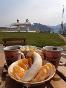 une assiette avec une banane et des oranges sur une table avec deux tasses dans l'établissement Family Hotel Belvedere, à Dŭlgopol