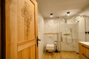 uma casa de banho com um chuveiro e uma porta de madeira em Rent like home - Za Cieszynianką 3 em Zakopane
