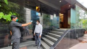 two men wearing masks standing in front of a building at Hotel Amigo in Mumbai