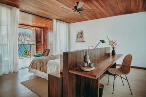 a bedroom with a bed and a desk and a window at Barracuda Hotel & Villas in Itacaré