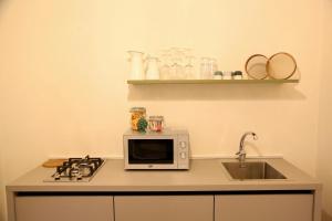 un bancone della cucina con forno a microonde e lavandino di DimorAruci - Ospitalità Siciliana a Modica