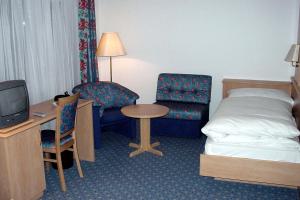 ザース・グルントにあるエデンのベッド、テーブル、椅子が備わるホテルルームです。