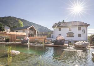 a house with a pond in front of a building at Hotel Weiler - Aktiv & Tradition in Obertilliach