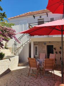 a patio with two chairs and a table with a red umbrella at Apartmani Adam in Primošten