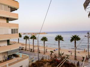 widok na plażę z palmami i budynek w obiekcie Bonefish Apartment w mieście Villajoyosa