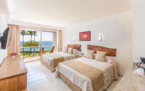 a hotel room with two beds and a view of the ocean at Posada Real Puerto Escondido in Puerto Escondido
