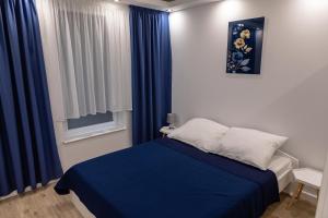 1 dormitorio con cama azul y cortinas azules en Apartament na Rybackiej en Kołobrzeg