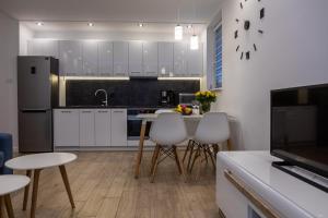 a kitchen with white cabinets and a table and chairs at Apartament na Rybackiej in Kołobrzeg