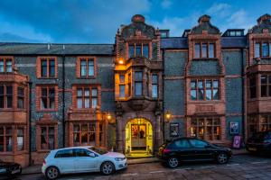 due auto parcheggiate di fronte a un grande edificio in mattoni di The Castle Hotel, Conwy, North Wales a Conwy